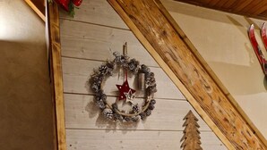 A fireplace with a stone surround, a wooden mantel, and a Christmas wreath with pinecones and stars. - Chalet de l'écureuil, petanque ground in the Vosges mountains near Gérardmer and Alsace (Anould)