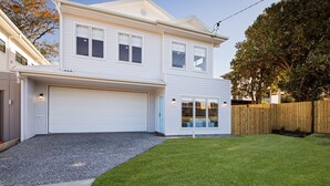 Et toetagers hus med hvide facader, en carport og en indhegnet have.