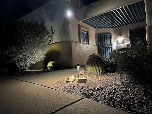 A building with a concrete pathway, a cactus, and a small lamp post.