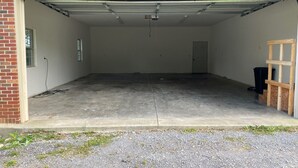 A garage with a concrete floor, a wooden ladder, and a black trash bin. - Bring Your Boat, Pets and Adventurous Spirit- Located Near It All (Guntersville)