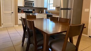 A kitchen with white cabinets, a stainless steel refrigerator, a microwave, and a stove. There is a dining table with chairs. - Bring Your Boat, Pets and Adventurous Spirit- Located Near It All (Guntersville)