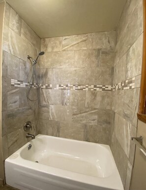 Ein Badezimmer mit einer Badewanne, einer Dusche und gefliesten Wänden.