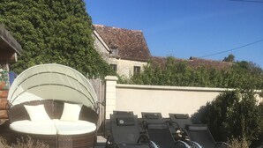 A patio area with a cushioned seating area, lounge chairs, and a small water feature.