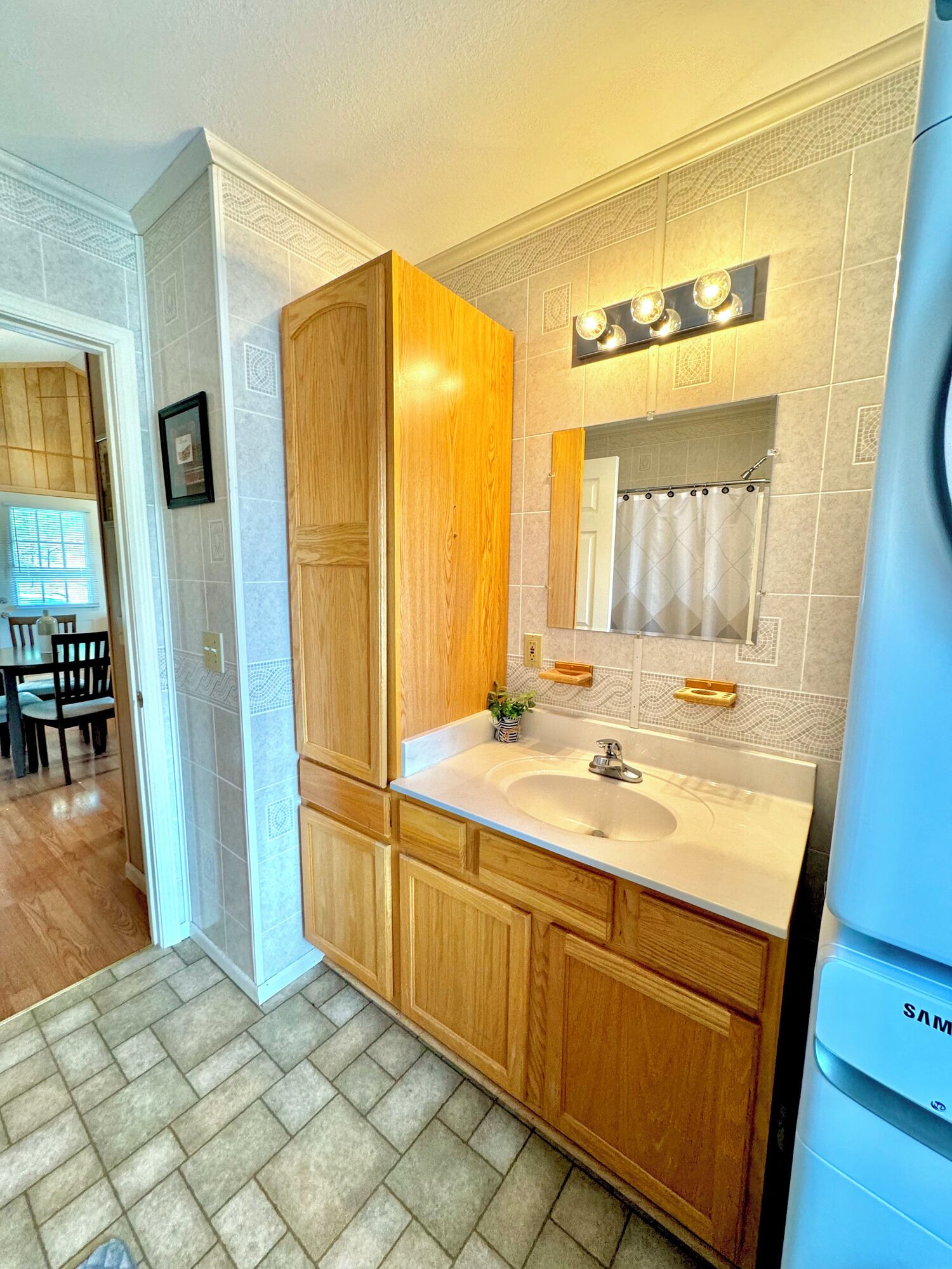 A modern bathroom with wooden cabinetry, a double sink, and a mirror with lights above.