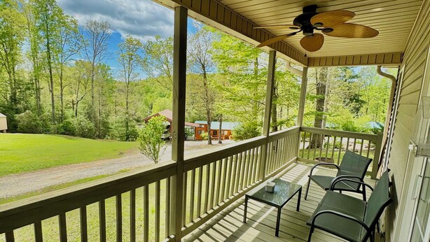 A covered porch with a ceiling fan, wooden railing, and a view of a green landscape. - Walking Distance to Lake James: Private Resort Amenities  (Marion)