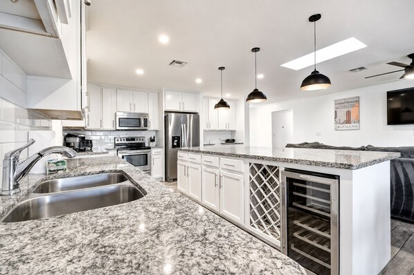 A modern kitchen with granite countertops, stainless steel appliances, and pendant lighting.