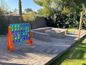 Un patio con un juego de mesa colorido, una chimenea y un sendero de ladrillos.