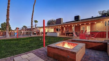 A backyard with a fire pit, outdoor seating, and a barbecue area.