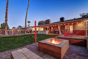 Un jardin avec un foyer, un espace salon extérieur et un coin barbecue.