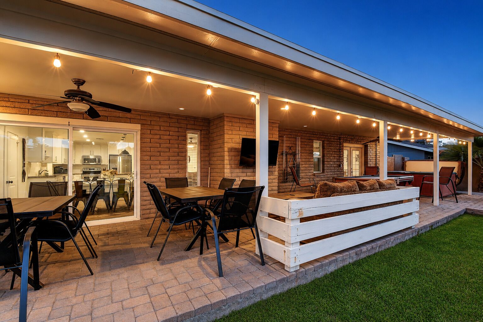 An outdoor patio with a dining table, chairs, and a white bench.