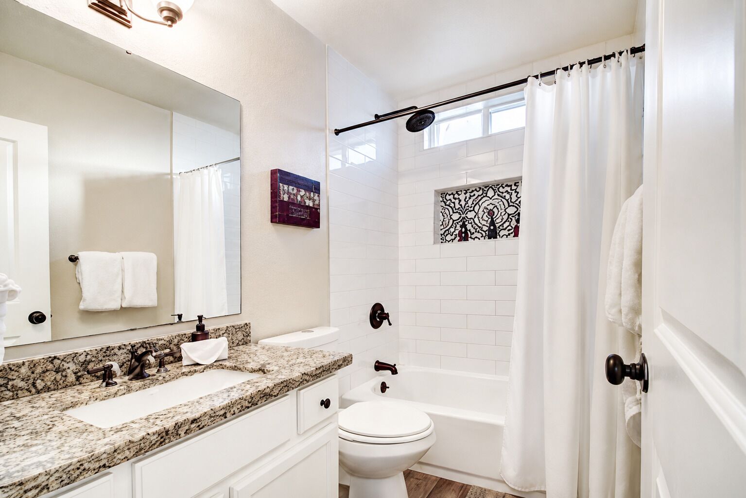 A bathroom with a marble countertop, a white toilet, a bathtub, and a shower curtain.