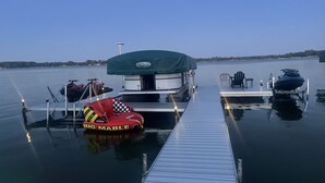 Un molo con una barca coperta, un jet ski e una barca gonfiabile rossa con la scritta "BIG MABLE".