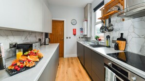 Une cuisine moderne avec un dosseret en marbre, un plancher en bois et un assortiment de produits pour le petit-déjeuner disposés sur le comptoir.