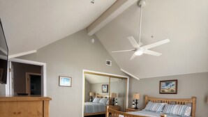 Ein Schlafzimmer mit zwei Betten, einem Deckenventilator und Holzboden.