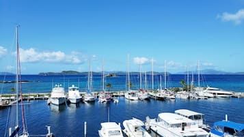 A marina with various boats docked, calm water, and a clear sky.