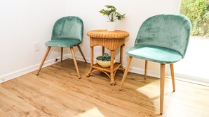 Two teal chairs with wooden legs, a wicker table with a white vase and a plant, and a wooden floor. - NEWLY RENOVATED SOPHISTICATED INDUSTRIAL TOWN HOME (St. Petersburg)