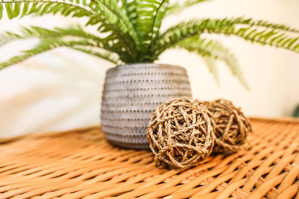 Een kamerplant in een pot met reliëf en twee bolvormige objecten op een geweven ondergrond.