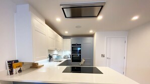 Une cuisine moderne dotée d’un îlot central, de meubles blancs et d’un four encastré.