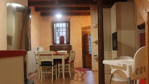 Une cuisine de taille réduite comprenant une table à manger, des chaises, un réfrigérateur et une fenêtre.