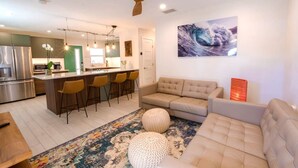 Une cuisine moderne dotée d’un îlot central, de tabourets de bar, d’un canapé et d’un ventilateur de plafond.