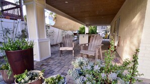 Un patio couvert avec des chaises en bois, des plantes en pot et une table en bois.