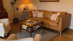 Un salon confortable avec un canapé, des fauteuils, une table basse et une lampe.