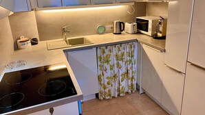 Une cuisine compacte équipée d’une cuisinière intégrée, d’un évier, d’un four à micro-ondes et d’un grille-pain.