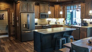 Een moderne keuken met houten kastjes, roestvrijstalen apparatuur en een groot kookeiland met krukken.