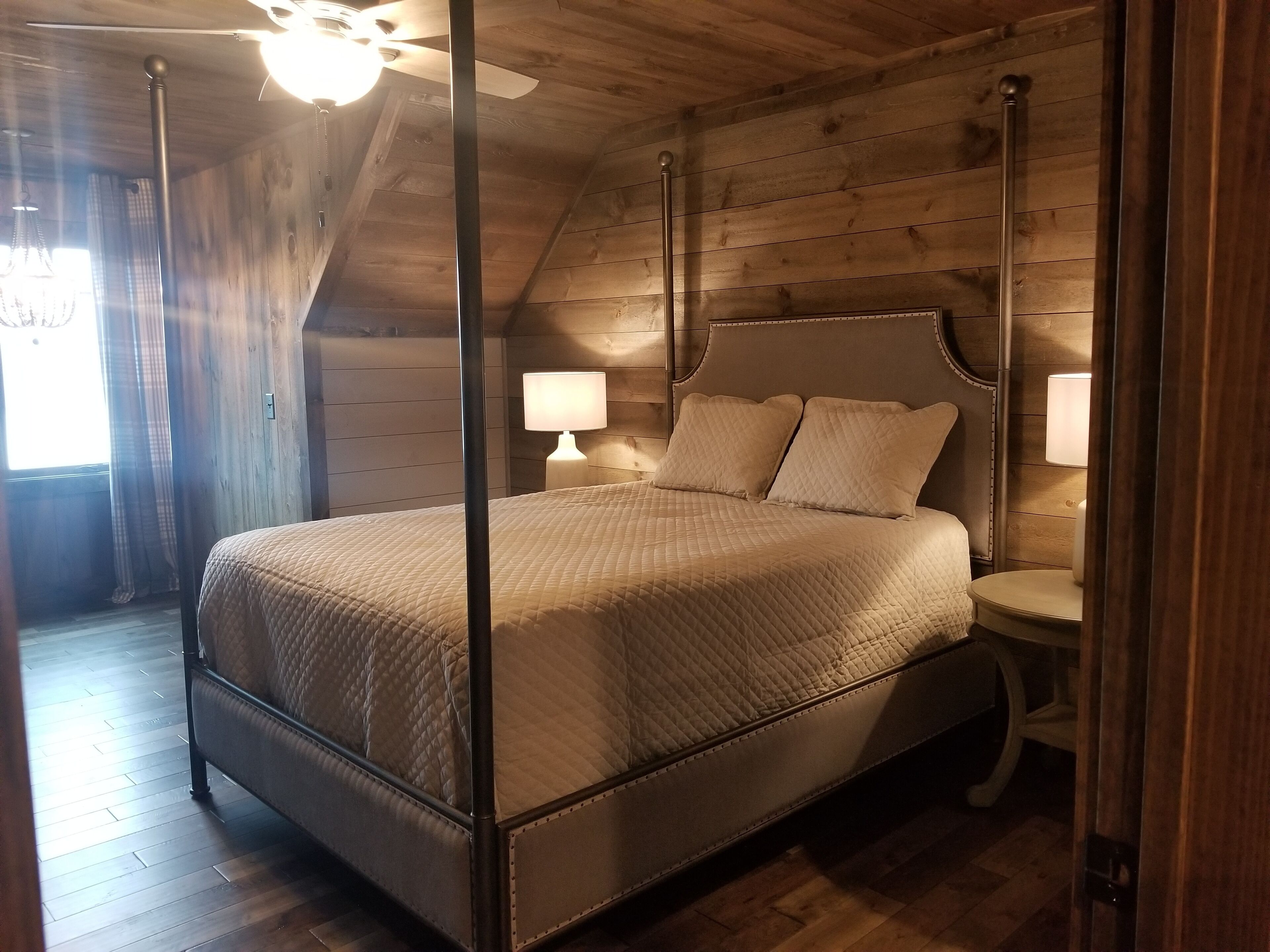 A bedroom with a bed, two bedside lamps, a nightstand, and a ceiling fan.