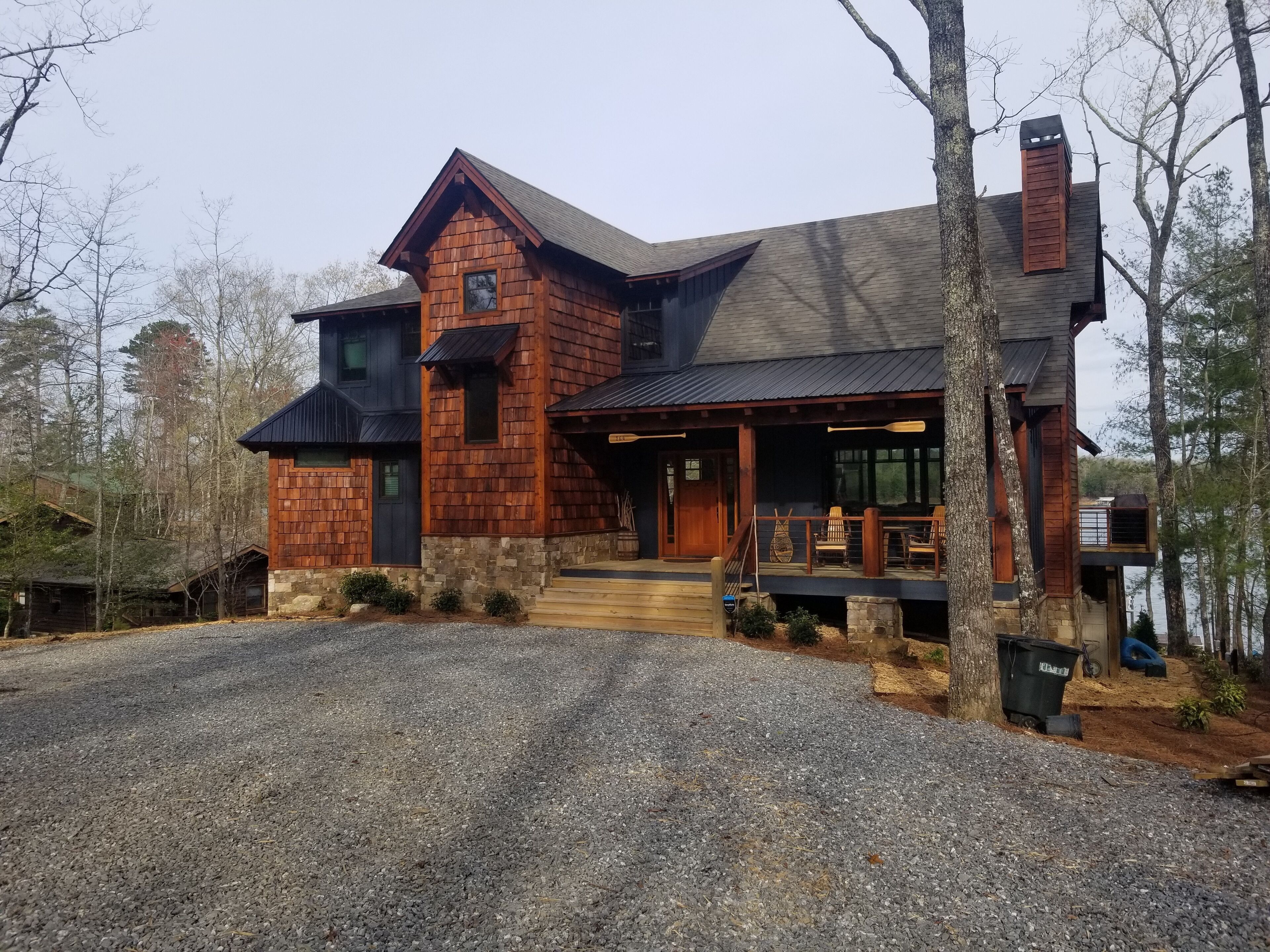Une cabane rustique avec des fondations en pierre, un revêtement en bois et une grande véranda dotée de meubles d’extérieur.