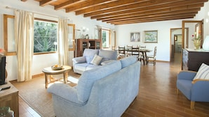 Amplia sala de estar con techo de madera, un sofá, una mesa de centro y un comedor con mesa y sillas.