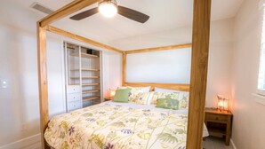 Une chambre à coucher avec un lit à baldaquin, des étagères intégrées et un ventilateur de plafond.
