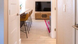 Un couloir étroit avec un coin repas et un téléviseur posé sur un meuble en bois.