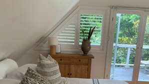 Une chambre à coucher avec un grand lit, une commode en bois et une fenêtre équipée de stores.