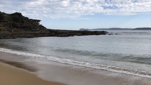 Une plage avec une rive sablonneuse et des falaises rocheuses en arrière-plan.