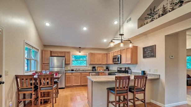 A spacious kitchen with wooden cabinets, stainless steel appliances, and a large island with bar stools. - Luxury lakefront apartment and private pool! Pool open Memorial Day - Labor Day. (Seneca Falls)