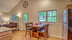 A kitchen with a dining table, chairs, a clock, and large windows with a view of trees. - Luxury lakefront apartment and private pool! Pool open Memorial Day - Labor Day. (Seneca Falls)