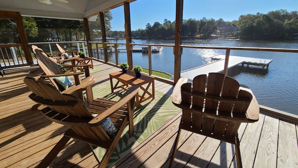 Une terrasse en bois, agréée de mobilier d’extérieur, donnant sur un lac.