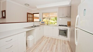 A modern kitchen with white cabinets, a stainless steel sink, and a built-in oven. - Close to beach and town in a quiet location.  (Busselton)
