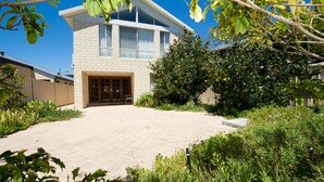 A two-story house with a paved driveway and a garden with various plants and shrubs. - Close to beach and town in a quiet location.  (Busselton)