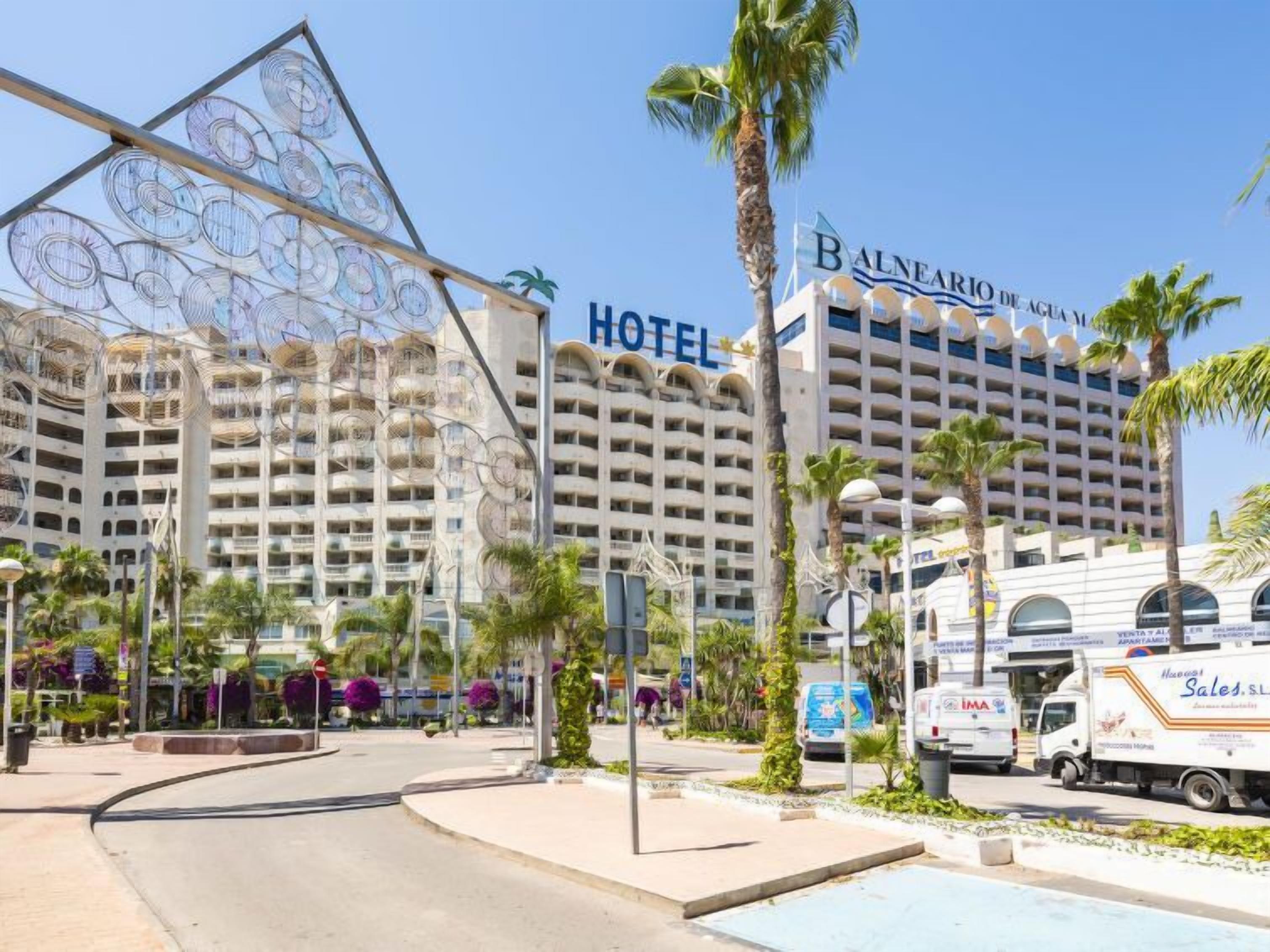 A hotel with multiple floors, a prominent sign, and a pool area.