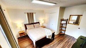 A neatly arranged bedroom with a wooden bed, bedside lamps, a mirror, and a wooden floor.