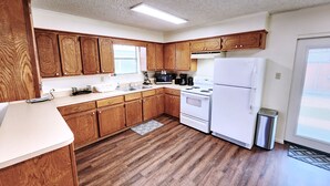 A kitchen with wooden cabinets, a white refrigerator, a stove, and a sink.