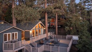 A two-story house with a deck, a fire pit, and a covered outdoor seating area.
