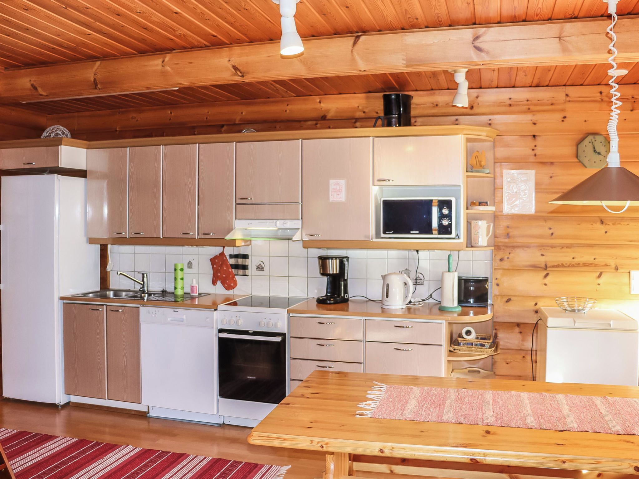 Une cuisine compacte avec des meubles en bois, un four à micro-ondes, une machine à café et un évier.