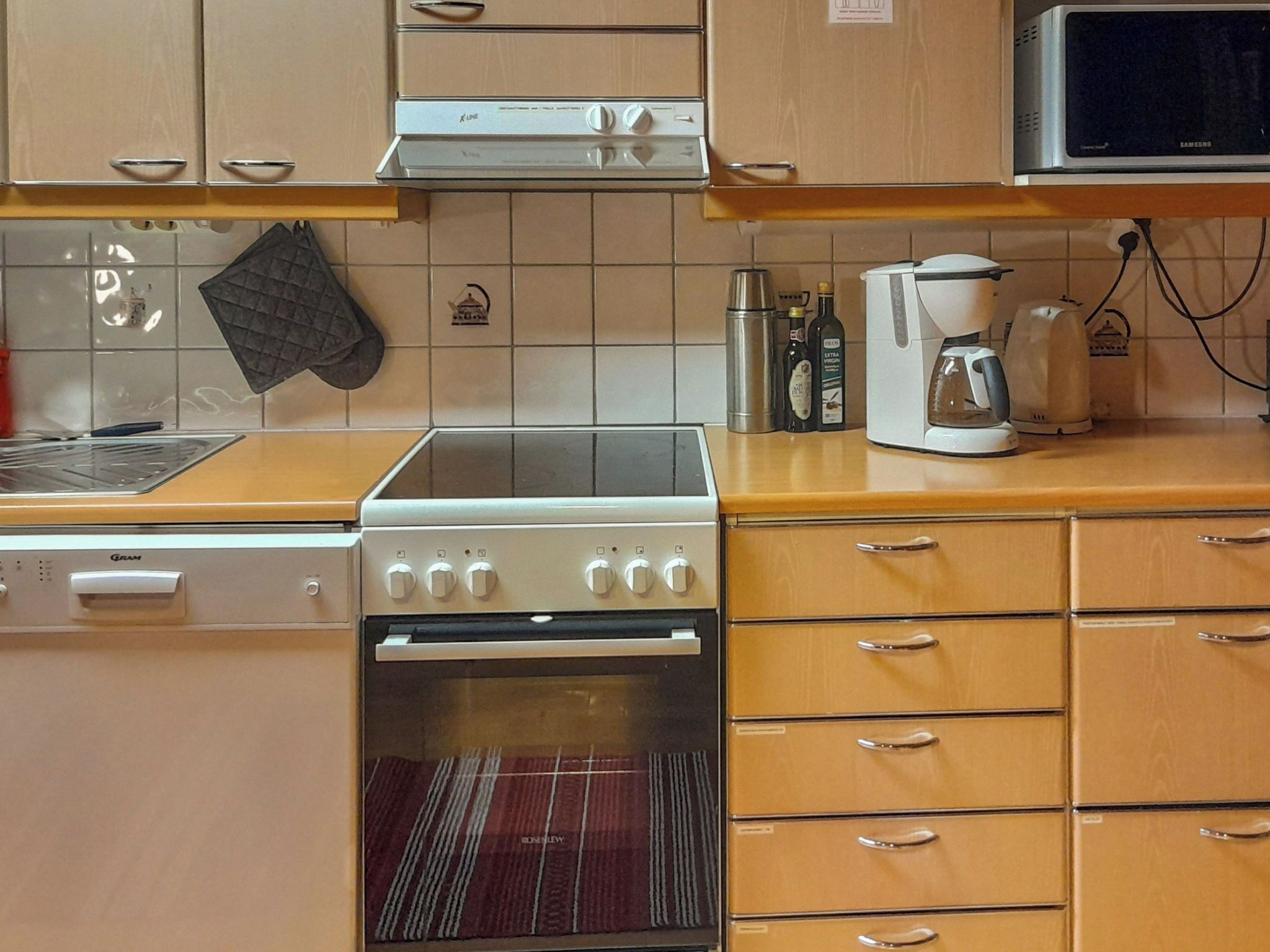 A kitchen with a stove, oven, microwave, and wooden cabinets.