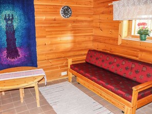 Un intérieur en bois avec un canapé, une petite table et une horloge murale.