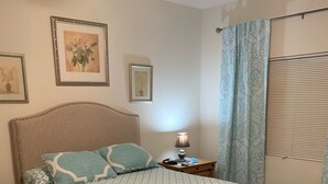 A neatly made bed with a patterned bedspread, a bedside lamp, and a nightstand with a lamp.