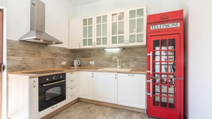 A kitchen with white cabinets, a red telephone booth, and a modern stove. - Nice home in Dugopolje with sauna (Dugopolje)