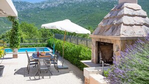 A pool area with a table and chairs, a stone oven, and a mountain view. - Nice home in Dugopolje with sauna (Dugopolje)